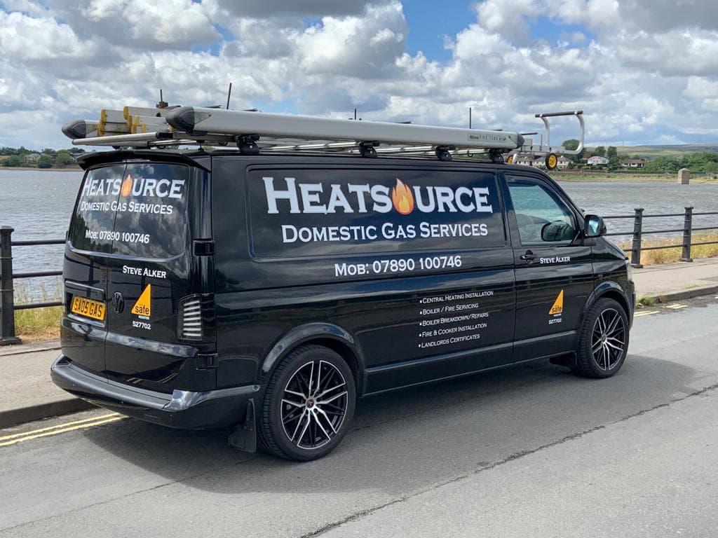 The Heatsource van parked by the water, liveried with the flame logo and phone number